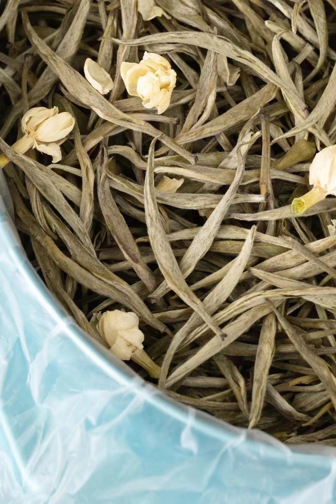 Tea leaves with small white flowers in a blue container